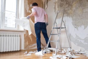 Caucasian,Man,Tearing,Off,Old,Wallpaper,From,Wall,Preparing,For